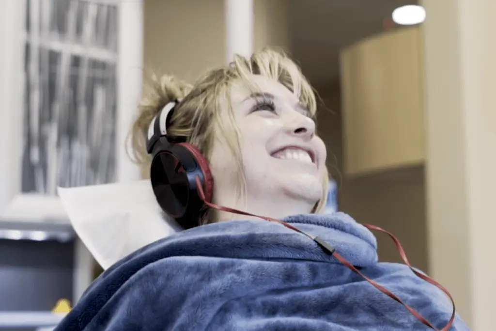 Patient smiling with blanket and watching Netflix in dental chair