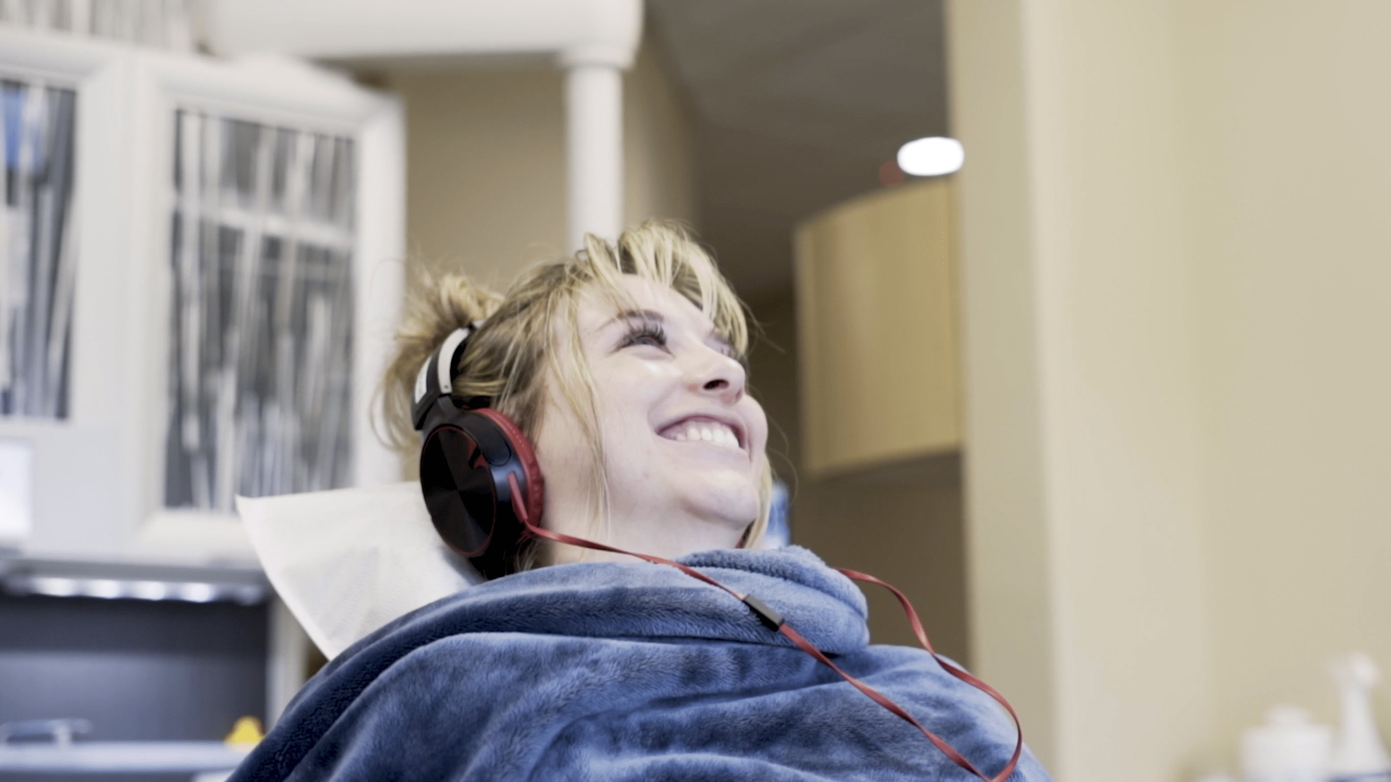 Patient smiling with blanket and watching Netflix in dental chair