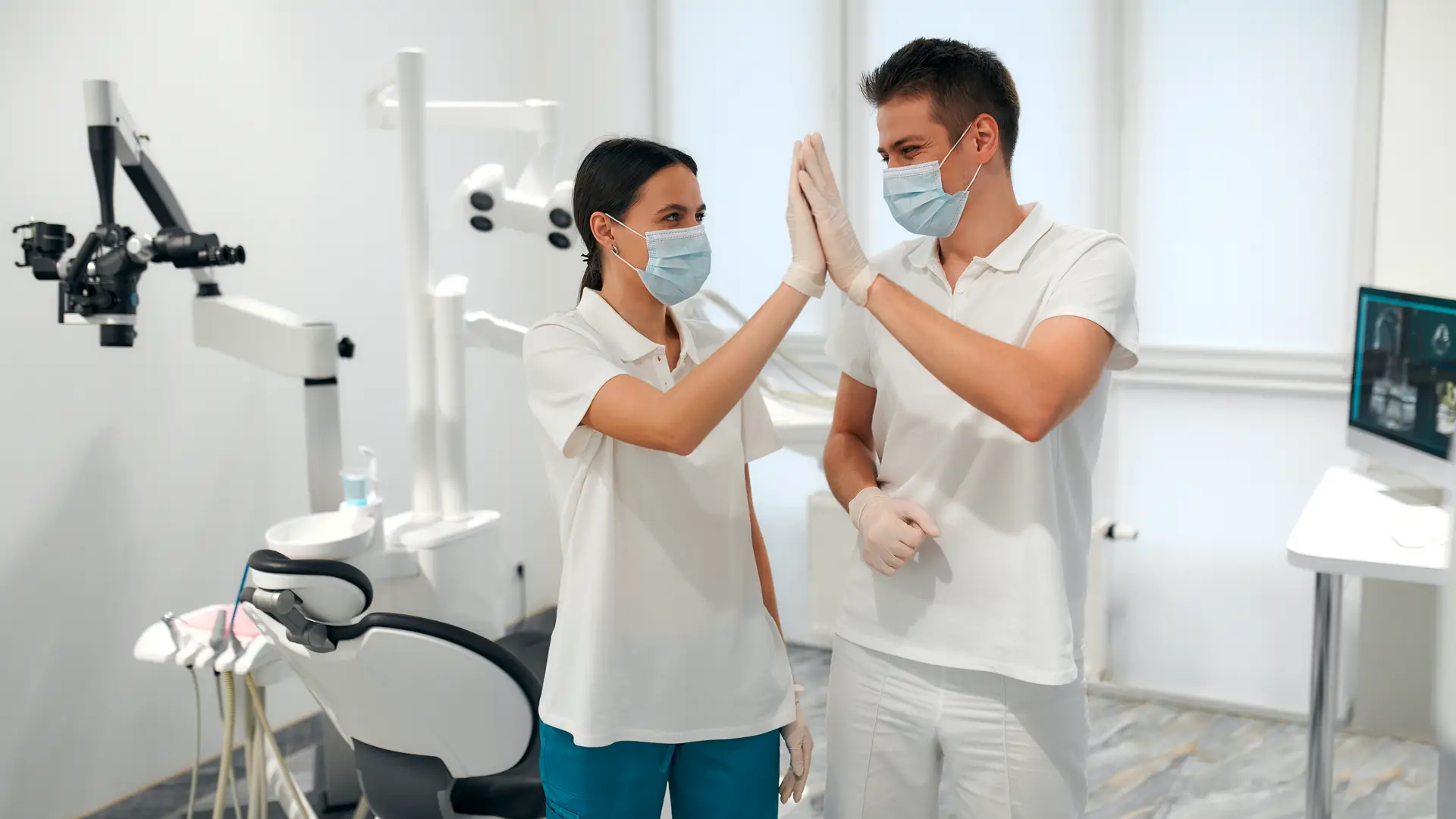 Dentist and patient high fiving at dental office. 